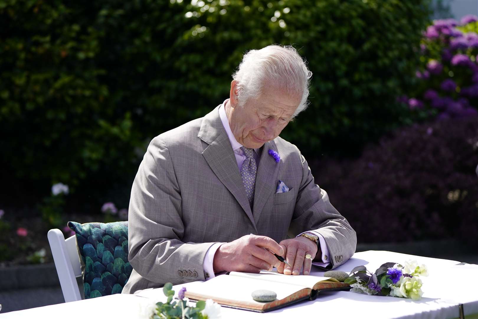 The King signs a book during a visit to Guernsey last summer (Andrew Matthews/PA)